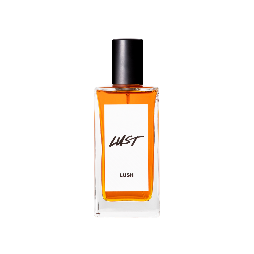 A glass perfume bottle filled with deep, reddish amber liquid. A white label reads 'Lust'.